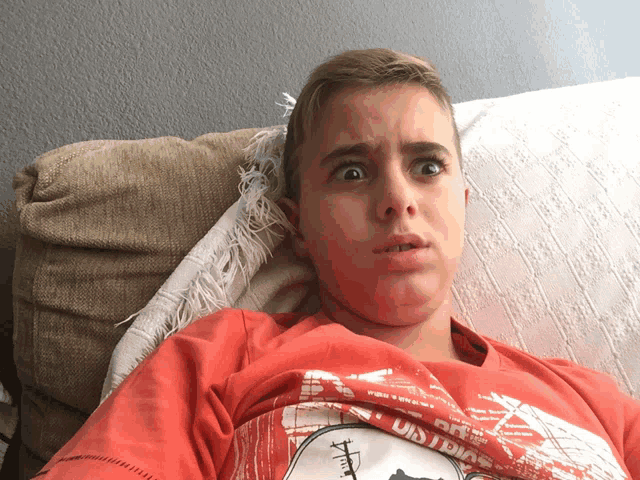 a boy laying on a couch wearing a red shirt that says u.s. army on it