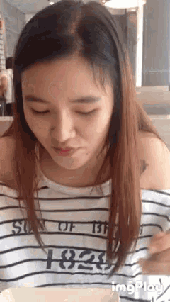 a woman wearing a striped shirt that says 1828 on it