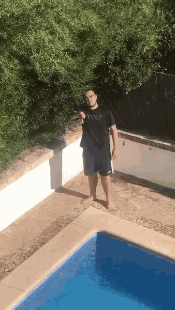 a man standing in front of a swimming pool wearing a black nike shirt