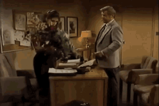 a man and woman are sitting at a desk in a room