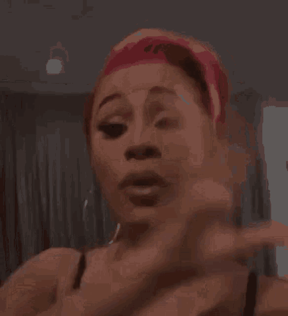 a woman with pink hair is making a funny face while wearing a head scarf .