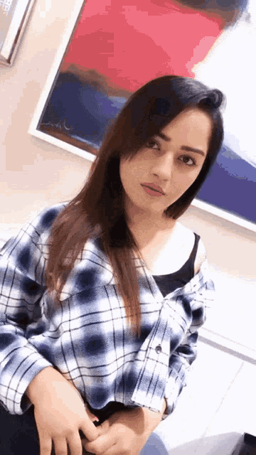 a woman in a plaid shirt is standing in front of a framed picture