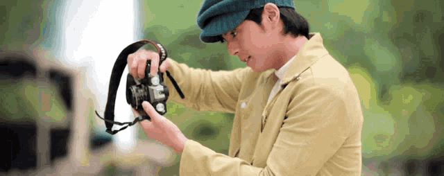 a man wearing a hat is looking at a camera strap