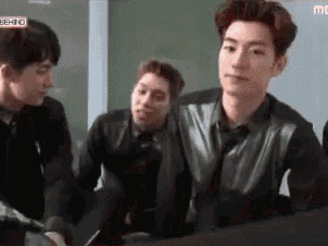 a group of young men are sitting around a table and talking .