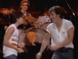 two men are dancing in front of a drum set in a dark room