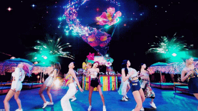 a group of women are dancing in front of a colorful balloon in the sky .