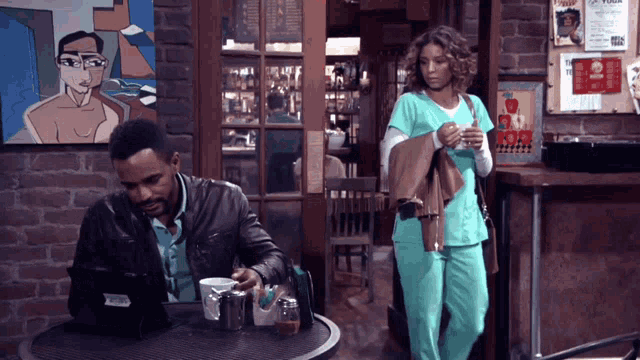 a man in a leather jacket sits at a table with a woman in scrubs