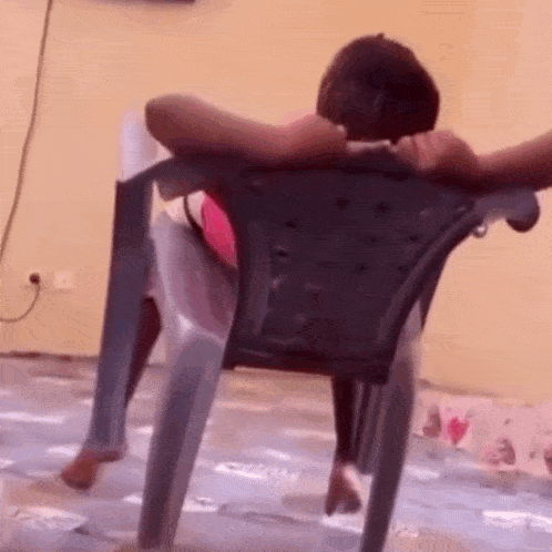 a person is sitting in a chair with their head resting on the back of the chair .