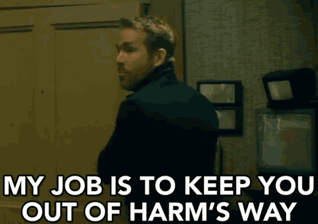 a man in a suit is standing in front of a door and says `` my job is to keep you out of harm 's way ''
