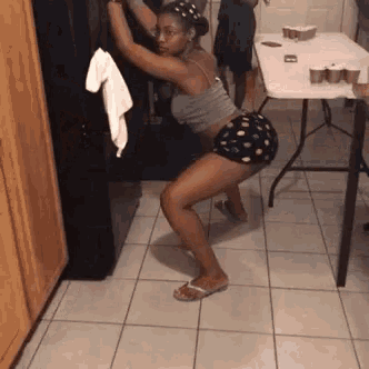 a woman squatting on a tiled floor in front of a fridge