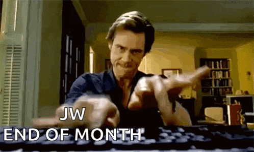 a man is typing on a keyboard and pointing at the camera with the words jw end of month .