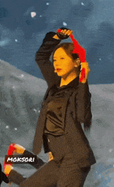 a woman in a suit is holding a red object in her hand while dancing on a stage .