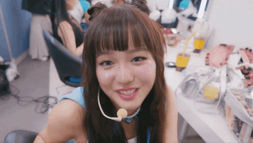 a girl wearing a microphone around her neck smiles for the camera
