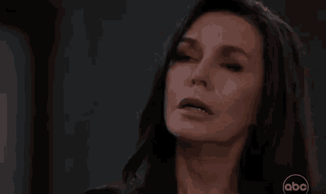 a close up of a woman 's face with a serious look on her face in a dark room .