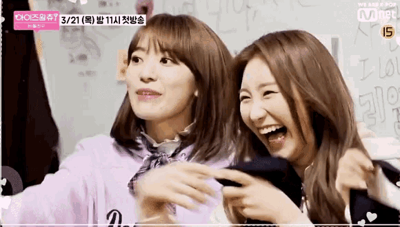 two girls are laughing together in front of a sign that says i love you