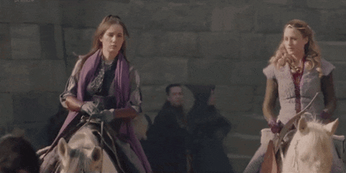a woman in a purple scarf is riding a white horse .