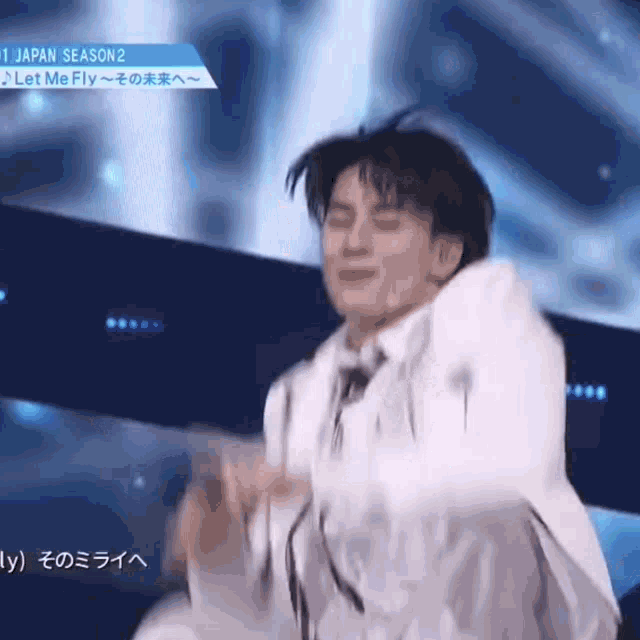 a man in a white suit is dancing on a stage in front of a blue background .