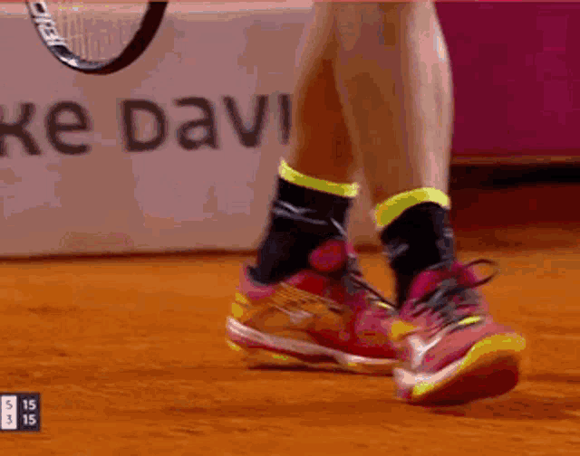 a tennis player 's feet are shown with a sign that says ke davi in the background