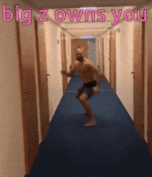 a shirtless man is dancing in a hallway with the words " big z owns you " above him