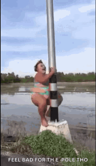 a woman in a bikini is standing on top of a pole .