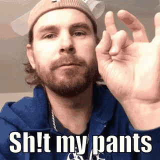 a man with a beard and a hat is giving the middle finger and saying `` shit my pants '' .