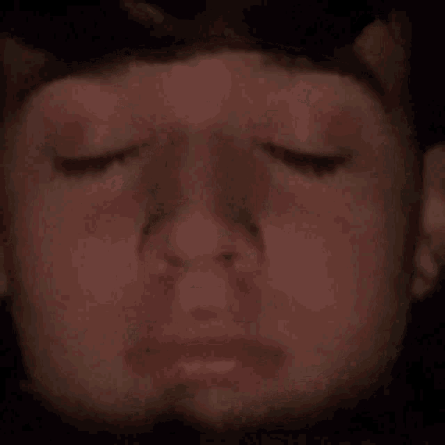 a close up of a young boy 's face with his eyes closed .