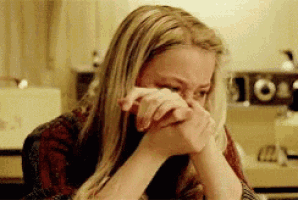 a woman is sitting at a table with her hands on her face and crying .