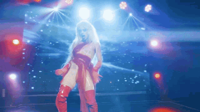 a woman in a red dress is dancing in front of a blue light