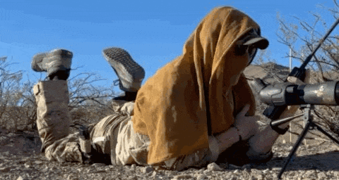 a man is laying on the ground holding a rifle