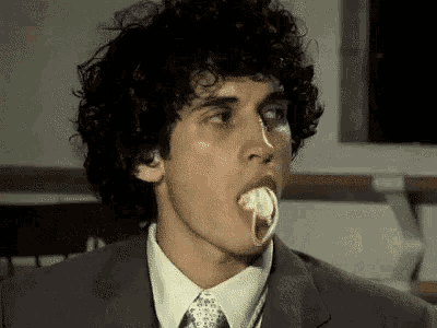 a man in a suit and tie is eating a piece of food .