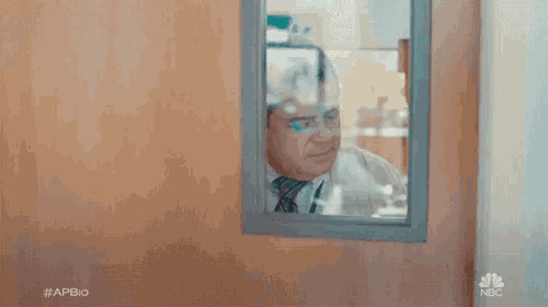 a man is looking at himself in a mirror in a room .