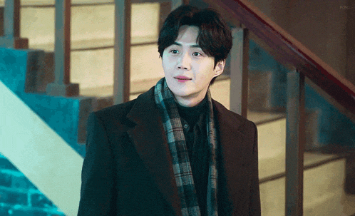 a man in a suit and scarf is standing next to stairs