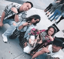 a group of people posing for a picture on a sidewalk with flowers .