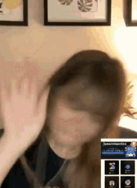 a woman is giving a high five while sitting in front of a wall with framed pictures on it .