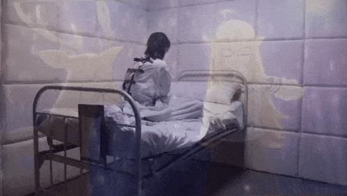 a woman in a straight jacket sits on a bed