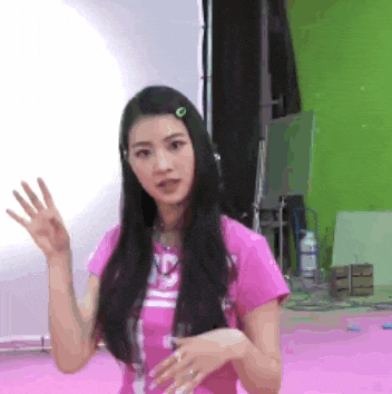 a woman in a pink shirt is waving her hand .