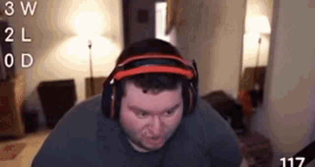 a man wearing headphones is sitting in a living room with the number 117 in the corner .