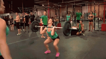 a woman squatting with a barbell over her head in a gym