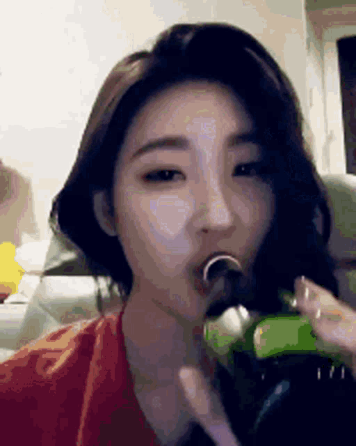 a woman is drinking from a green bottle .