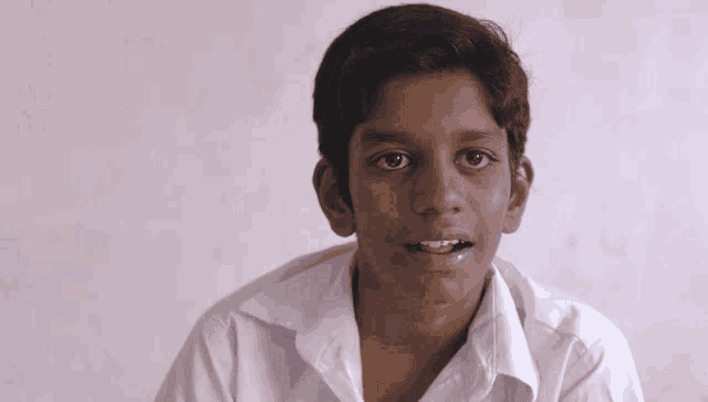 a boy in a white shirt looks at the camera