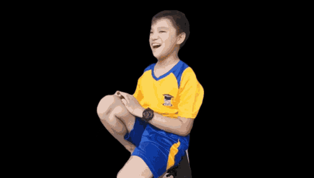 a boy in a yellow shirt and blue shorts is clapping