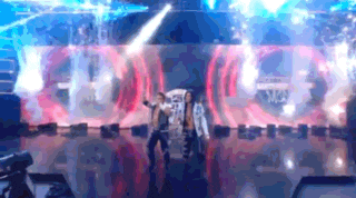 two people are dancing on a stage in front of a large screen that says ' a ' on it .