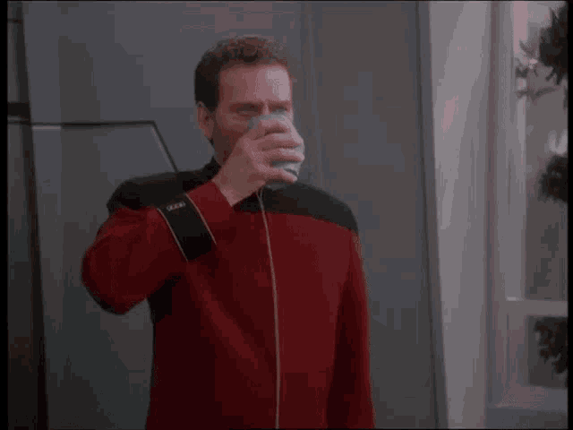 a man in a red jacket holds a glass with the letter o on the sleeve