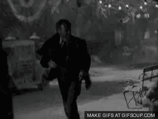 a black and white photo of a man walking down a snowy street .