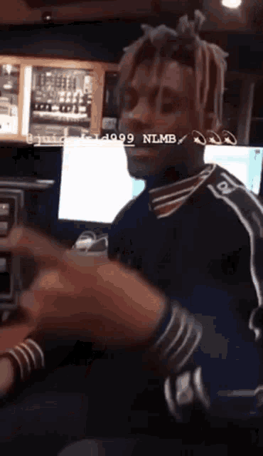 a man with dreadlocks is sitting in front of a computer with the letters nlmb on the bottom