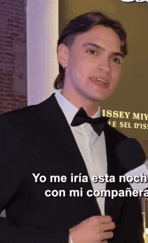 a man wearing a tuxedo and bow tie is speaking in spanish