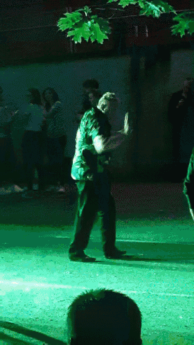 a group of people are dancing in a dark room with a green light behind them