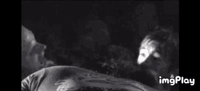 a black and white photo of a person laying down with their eyes closed .