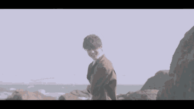 a man in a suit is standing on a rocky beach