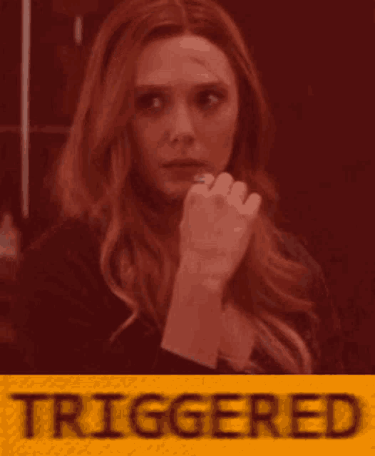 a woman with red hair is standing in front of a yellow sign that says triggered
